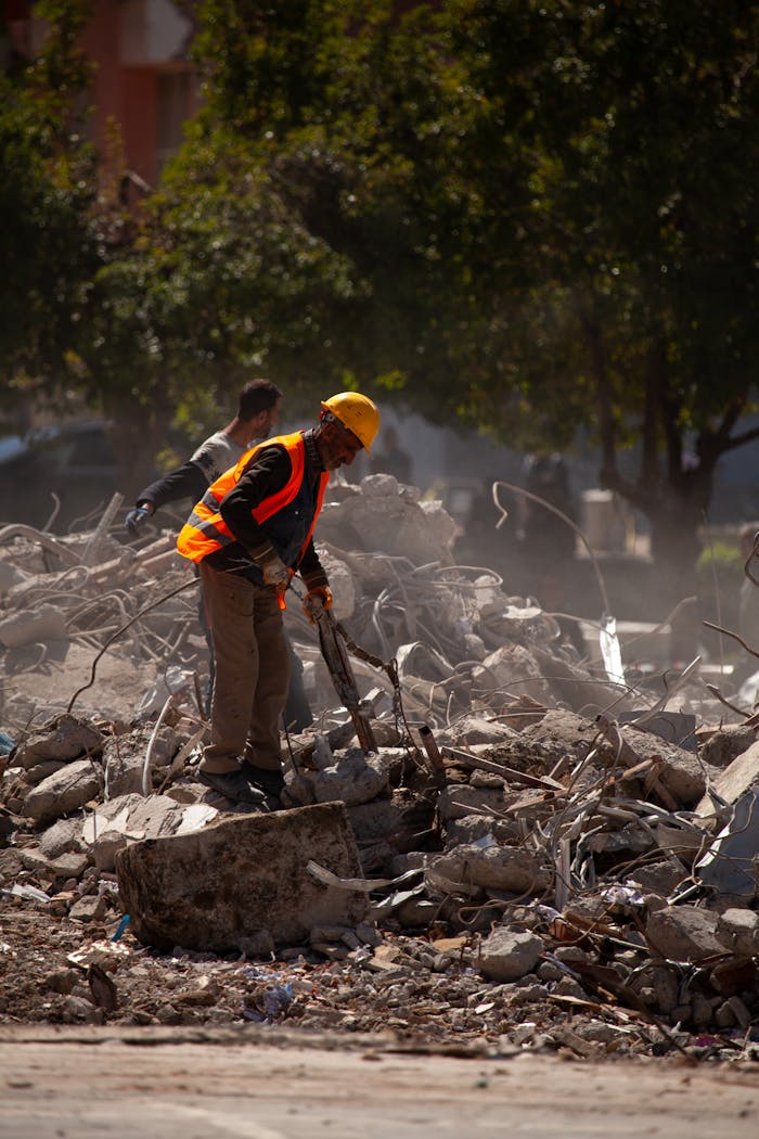 Worker in safety gear clearing debris after demolition in Malatya, Türkiye.